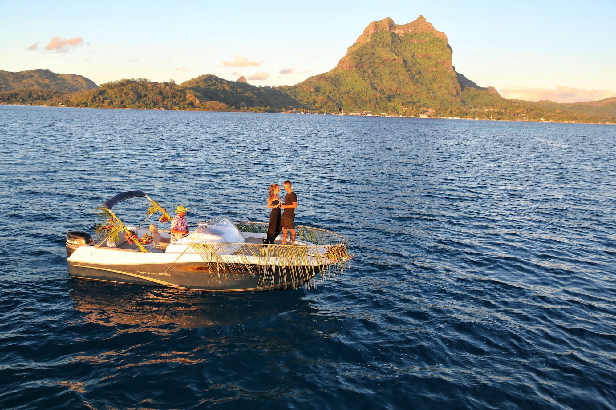 Couple toasting on a Bora Bora sunset catamaran sail with Mount Otemanu in the background